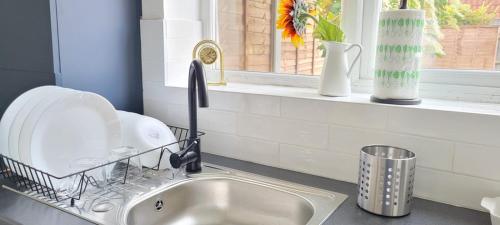 Un fregadero de cocina con mezclador y ventana. en Luxury 2 Bedroom Home Dagenham, en Dagenham