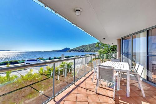 a balcony with a table and chairs and a view of the water at Palm Beach 33B Shoal Bay Road in Shoal Bay