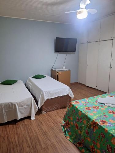 a room with two beds and a flat screen tv at hospedagens regina in Águas de Lindóia