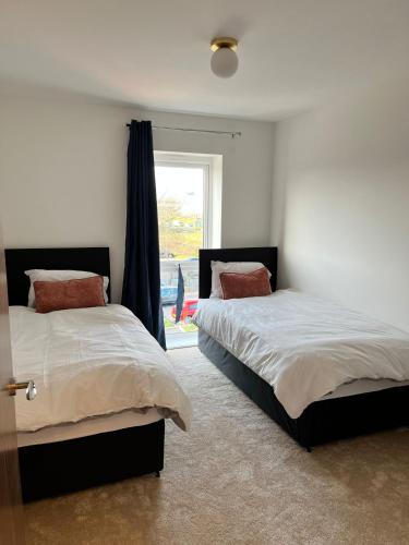 two beds in a room with a window at Lakeside Apartment - 2 Bed, Free Parking in West Thurrock