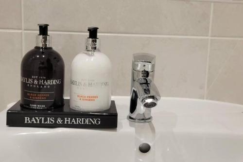 two bottles of alcohol sitting on a bathroom sink at Lakeside Apartment - 2 Bed, Free Parking in West Thurrock
