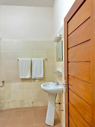 baño con lavabo blanco y puerta de madera en Simple Ecomomy Room in Cotonou, en Mama