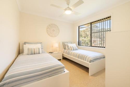 two beds in a room with a window at The Verandah fantastic child friendly home in Anna Bay