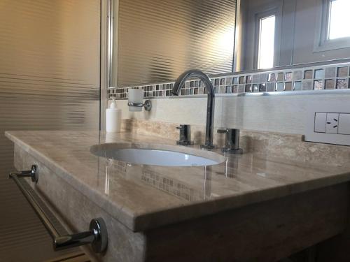 Un mostrador de baño con un lavabo y un espejo. en Luxury Apart, en Villa María