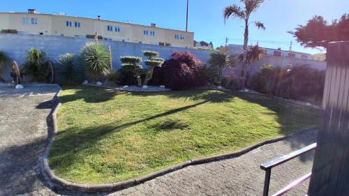 a grassy yard with palm trees and a building at Cute House Marinho in Santa Maria da Feira