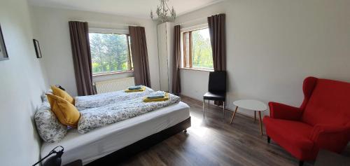 a bedroom with a bed and a red chair at Cora´s House & Horses in Ölfus