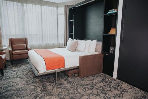 a hotel room with a bed and a chair at The Parker Hotel and Rooftop in Vancouver