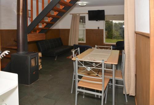 a living room with a wood stove and a table at Cabañas Bosque Sur in Puerto Varas