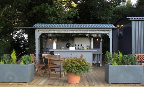 an outdoor kitchen with a bar on a deck at Top Farm Shepherds Lodge in Marsham