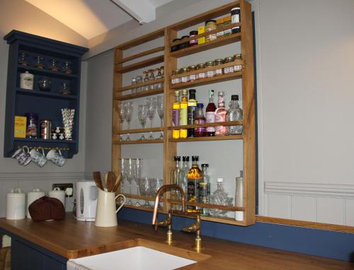 a kitchen with a sink and a counter with alcohol bottles at Top Farm Shepherds Lodge in Marsham
