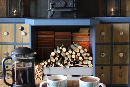 two cups of coffee sitting on a table next to a fireplace at Top Farm Shepherds Lodge in Marsham