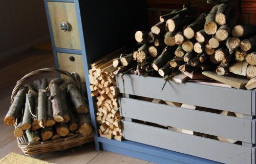 a pile of fire wood next to two trunks at Top Farm Shepherds Lodge in Marsham