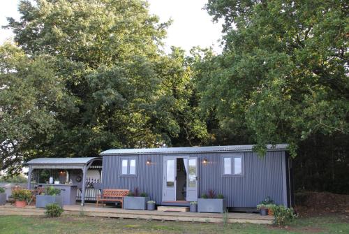 a tiny house with a porch in a yard at Top Farm Shepherds Lodge in Marsham