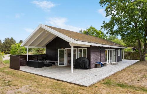 a black house with a wooden deck in a field at 5 Bedroom Awesome Home In Grenaa in Grenå