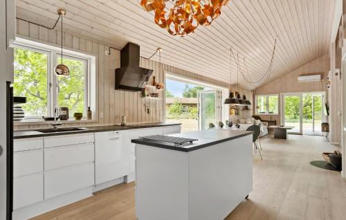 a large kitchen with white cabinets and a chandelier at 5 Bedroom Awesome Home In Grenaa in Grenå