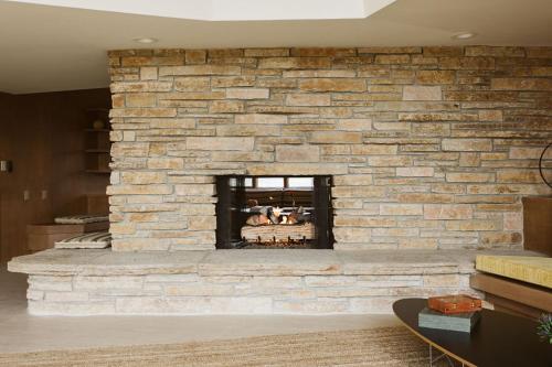 a stone fireplace in a living room at Frank Lloyd Wright student built riverfront home in Manitowoc