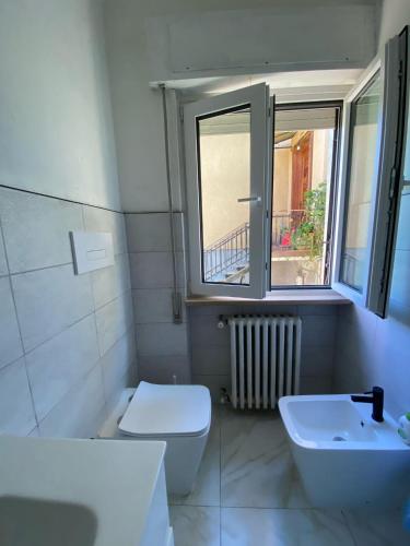 a bathroom with a toilet and a sink and a window at Villa la Palma in Gemonio