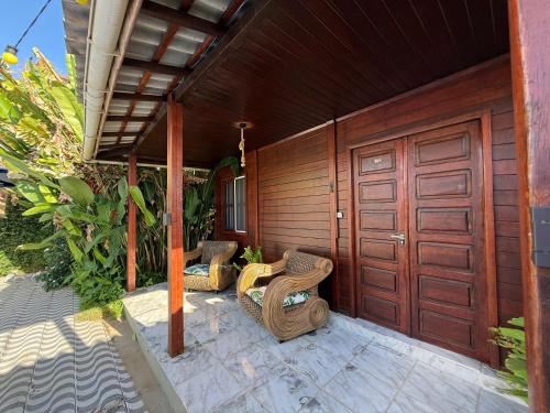 a patio with two wicker chairs and a wooden door at Pousada das Flores in Fernando de Noronha