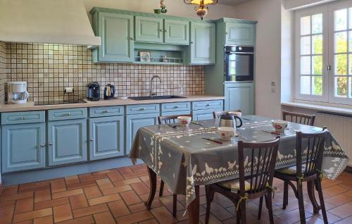 une cuisine avec des placards bleus et une table avec des chaises dans l'établissement 4 Bedroom Awesome Home In Plouigneau, à Plouigneau