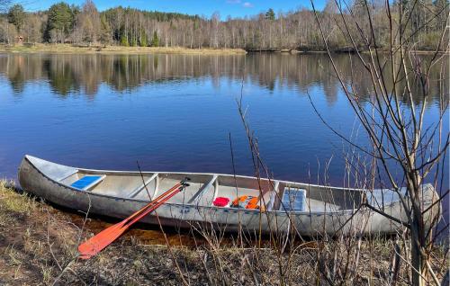 a boat sitting on the shore of a lake at 3 Bedroom Awesome Home In Stöllet in Stöllet