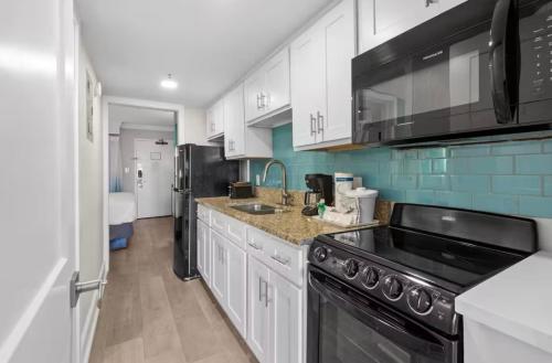 eine Küche mit weißen Schränken und schwarzen Geräten in der Unterkunft Grande Cayman 1BR Penthouse Patio Oceanfront Views in Myrtle Beach