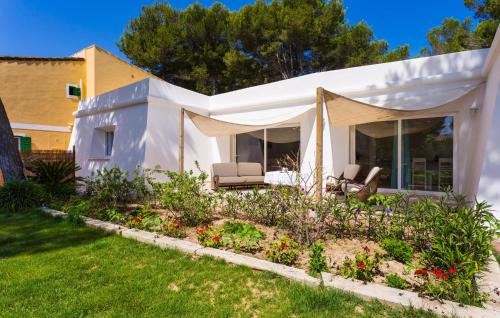 una casa blanca con dos sillas en un patio en Oasis Can Picafort, en Can Picafort
