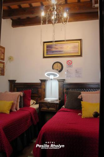 a bedroom with two beds and a clock on the wall at Hotel Rholyn Pura Vida!! in Antigua Guatemala