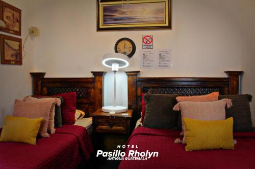 a bedroom with two beds and a clock on the wall at Hotel Rholyn Pura Vida!! in Antigua Guatemala