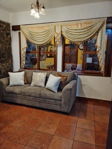 a couch sitting in a living room with windows at Hotel Rholyn Pura Vida!! in Antigua Guatemala