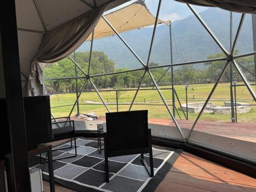 a room with two chairs and a view of a field at Domo Nool con vista a las estrellas in Río Blanco