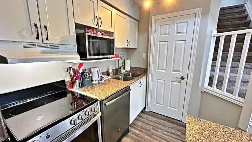 una cucina con mobili bianchi e un forno a piano cottura di Freshly Upgraded Cozy Loft @ North Creek Resort a Blue Mountains