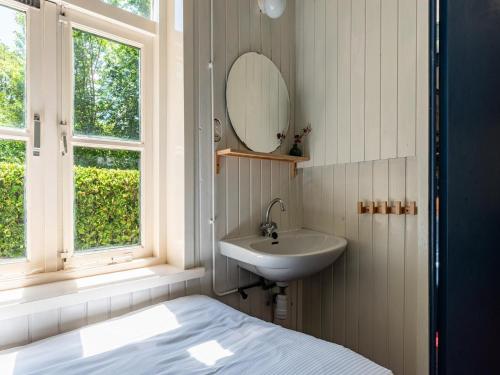 Un baño con lavabo, espejo y cama. en Holiday Home in Vrouwenpolder near Beach, en Vrouwenpolder