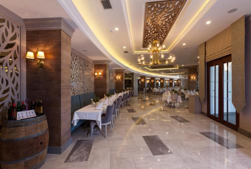 a restaurant with white tables and chairs and a chandelier at Samara Hotel Bodrum Ultra All Inclusive in Torba