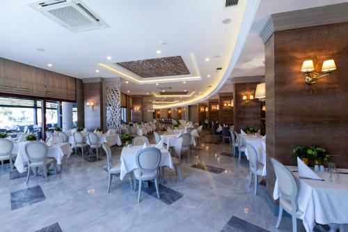 a dining room with white tables and chairs at Samara Hotel Bodrum Ultra All Inclusive in Torba