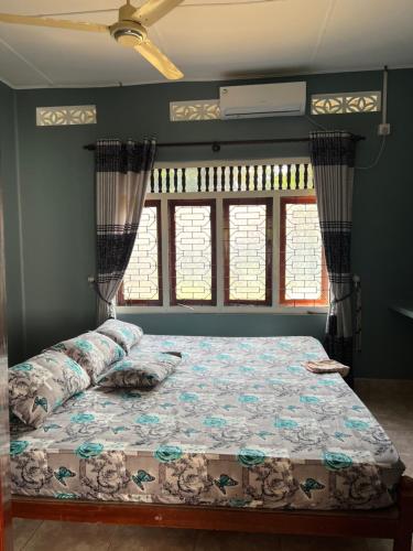 a bed in a room with two windows at 288 Jeyamany Villa in Jaffna