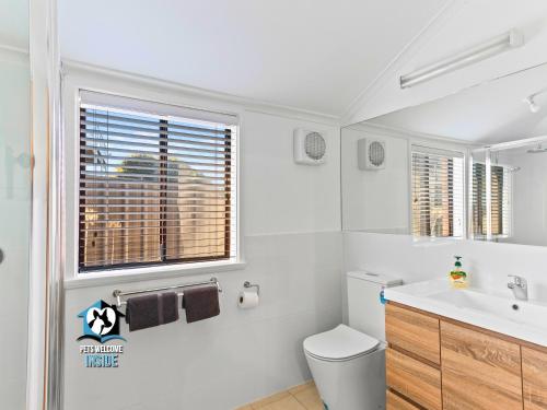 a bathroom with a toilet and a sink and a window at Absolute Beachfront 3BR 2BA Home w/ Beach Track in McCracken