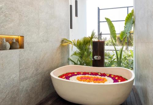 a bath tub filled with flowers in a bathroom at Botanika Estate Private Pool Villa in Canggu