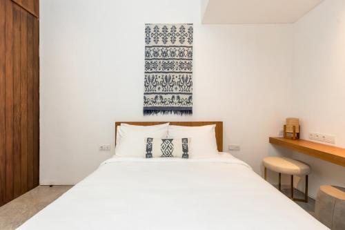 a bedroom with a large white bed and a desk at Botanika Estate Private Pool Villa in Canggu