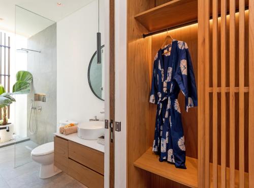 a bathroom with a wooden door with a robe on it at Botanika Estate Private Pool Villa in Canggu
