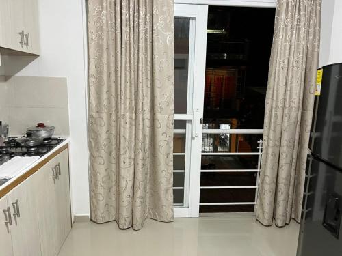 a kitchen with a window with curtains in a room at Tayra Living Suites in Mocoa