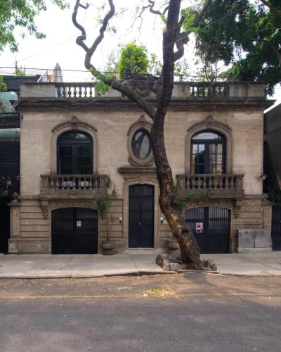 an old brick building with a tree in front of it at Livin Condesa in Mexico City