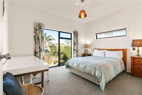 une chambre avec un lit, un bureau et une fenêtre dans l'établissement Island Views - Waihi Beach Holiday Home, à Waihi Beach
