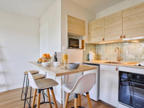 une cuisine avec un comptoir, des chaises et une table dans l'établissement Charmant deux pièces rénové avec balcon et parking à Cabourg - FR-1-788-75, à Cabourg