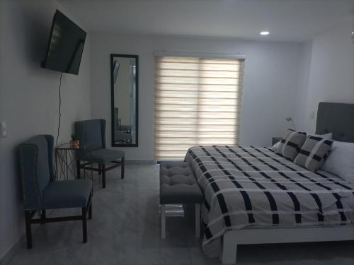 a bedroom with a bed and a television and chairs at The Residences by Morgan in Cabo San Lucas