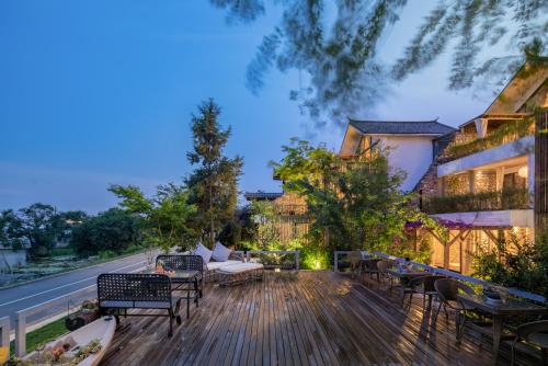 a deck with chairs and tables on a house at Munwood Dali Lanqing Designer Hotel in Dali Ancient Town