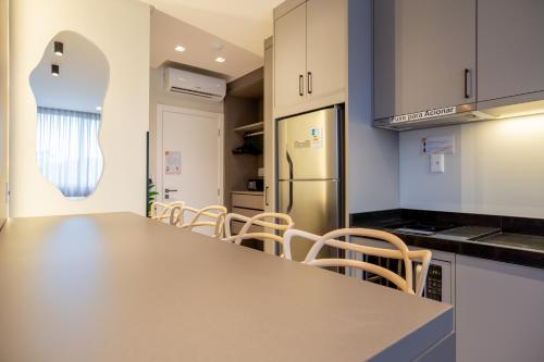 a kitchen with a counter and chairs and a refrigerator at Elegance - Piscina Aquecida - Apartamento para 4 pessoas em Bombinhas in Bombinhas