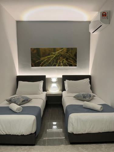 a room with two beds and a painting on the wall at White Lodge in Pantai Cenang