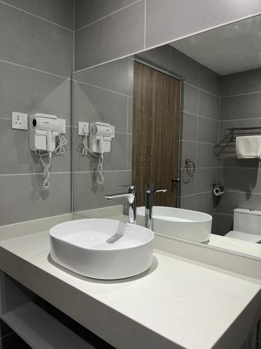 a bathroom with a white sink and a mirror at White Lodge in Pantai Cenang