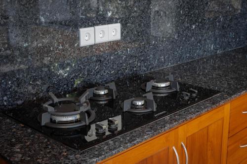 a stove top in a kitchen with black granite counter top at Sekarinis Place in Amed