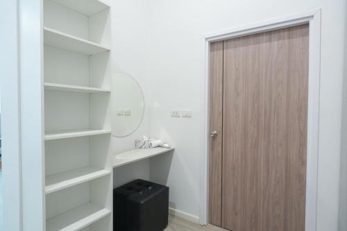 a bathroom with white shelves and a wooden door at GRAND PA Hotel&Resort Lamphun Chiang Mai in Lamphun